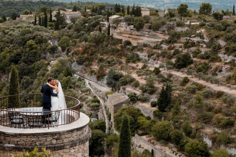 Bride and groom kissing on top of tower overlooking town in hills - Picture by Damion Mower Photography