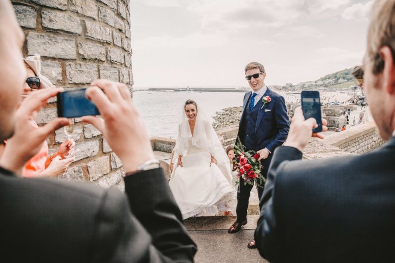 Wedding guests taking photos of bride and groom on their phones