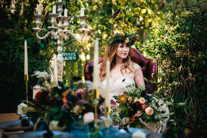 Bride sitting on red leather chair in woodland