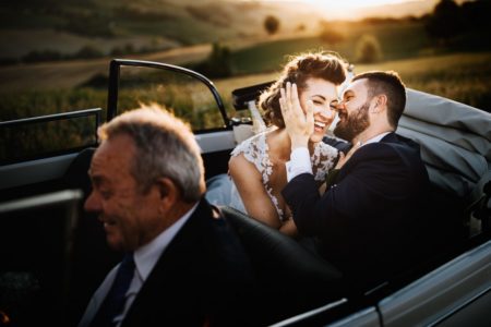 Bride and groom laughing in back of convertible wedding car - Picture by Nicola Tonolini