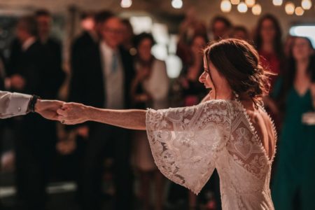 Bride stretching out arm to hold groom's hand during first dance - Picture by Ben Wigglesworth Photography