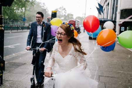 Happy bride and groom riding on scooters pulling balloons - Picture by Kristian Leven Photography