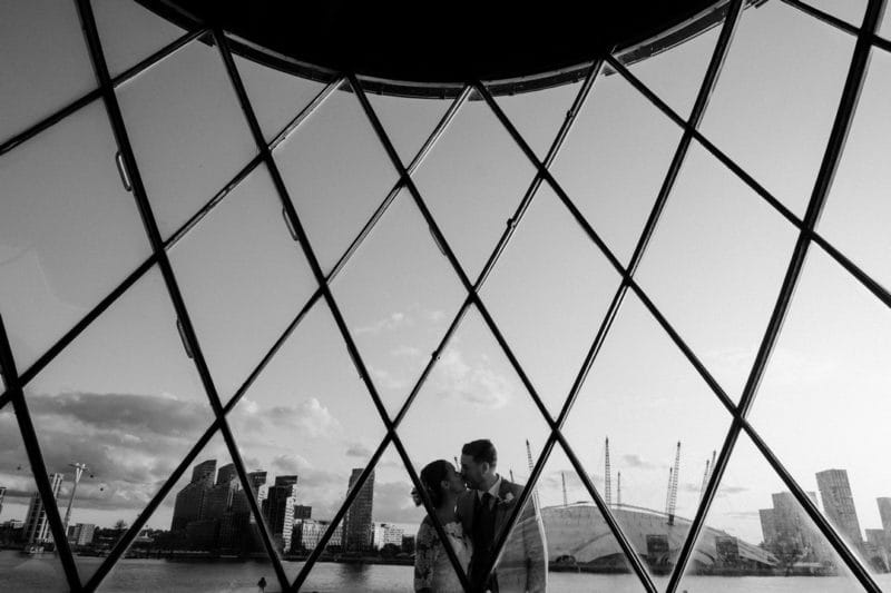 Bride and groom kissing with O2 Arena in background - Picture by Joasis Photography