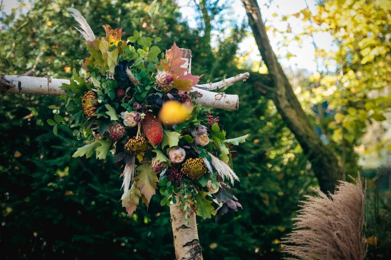 Autumnal flowers and foliage on corner of wedding ceremony arch