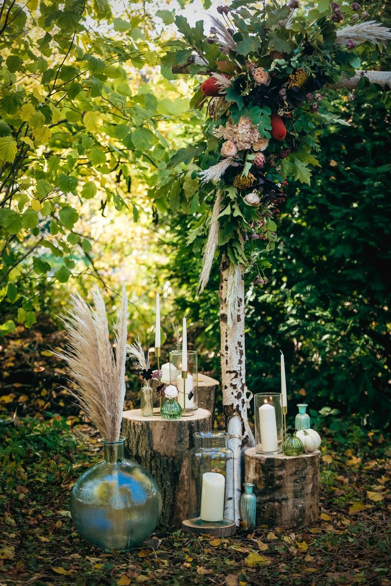 Candles and glass vases on stumps in woodland