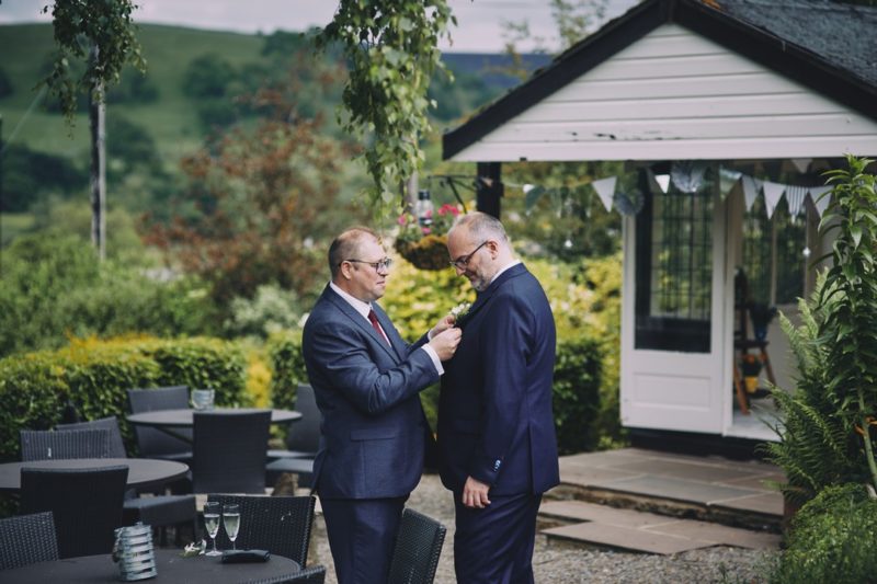 Best man helping groom put on buttonhole