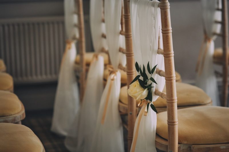 Flowers tied to sash on wedding chairs