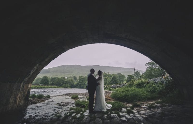 Bride and groom standing under bridge