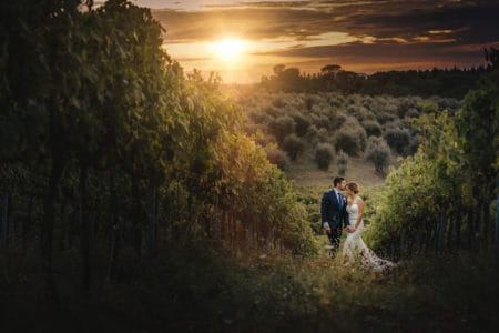 Groom kissing bride on head in beautiful countryside as sun sets - Picture by David West Photography