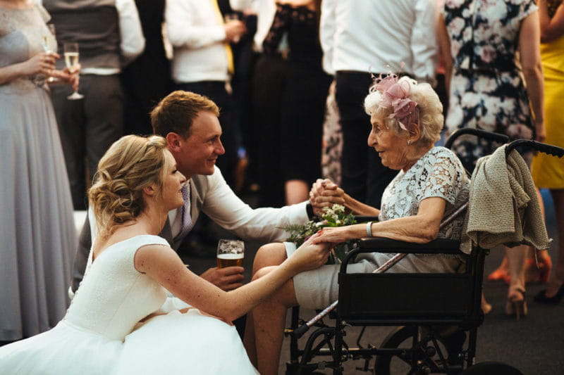 Bride and groom with elderly guest - Image by Lyndsey Goddard Photography