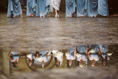 Bride and bridesmaids' legs with reflection of faces in puddle - Picture by Nick Ray Photography
