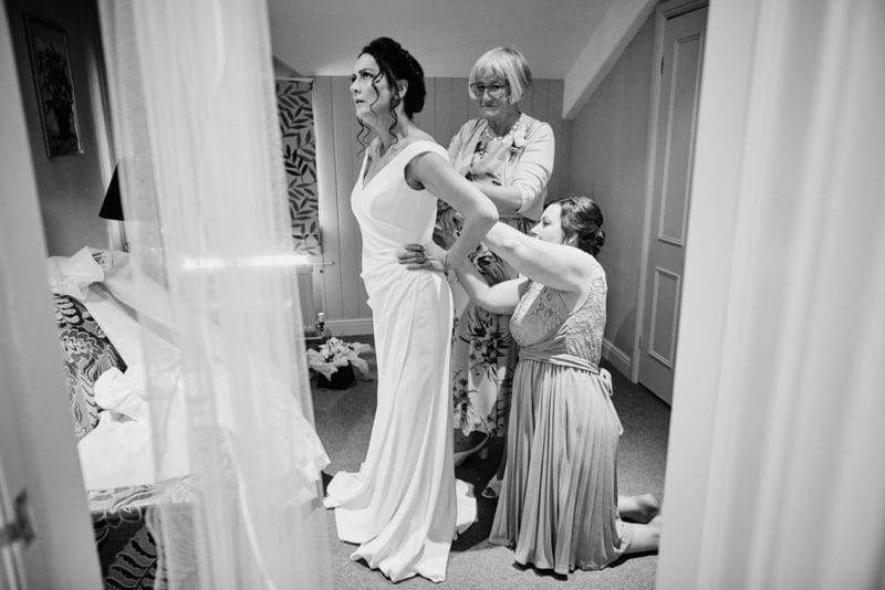 Ladies doing up back of bride's dress