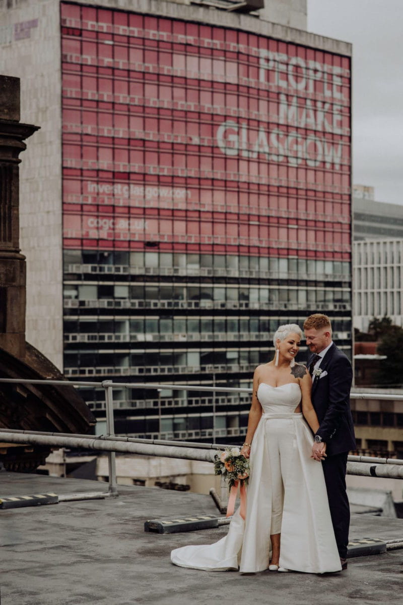 Bride and groom in front of tower block which says People Make Glasgow - Picture by Good Luck Wolf Photography
