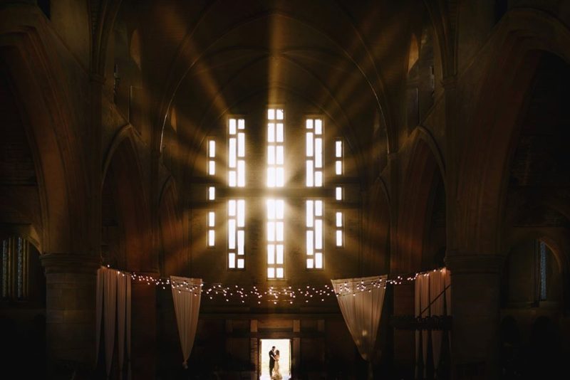 Bride and groomstanding in doorway of church as light shines through windows above them - Picture by Andy Gaines