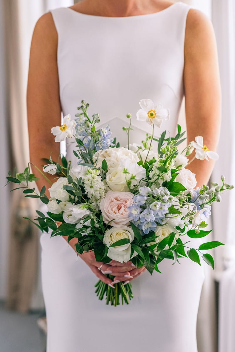Bridal bouquet with blue, white and pink flowers and green foliage