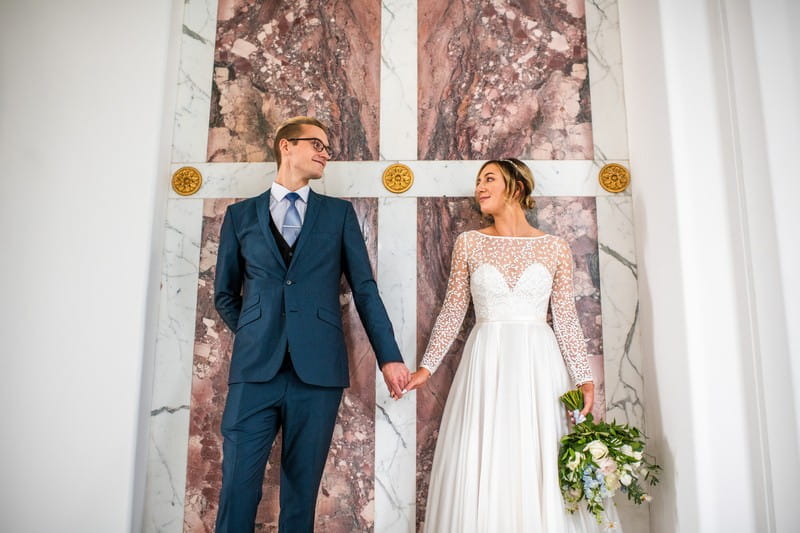 Bride and groom standing in front of marble backdrop