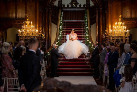 Bride walking down staircase into wedding ceremony - Picture by Peter Rollings Photography