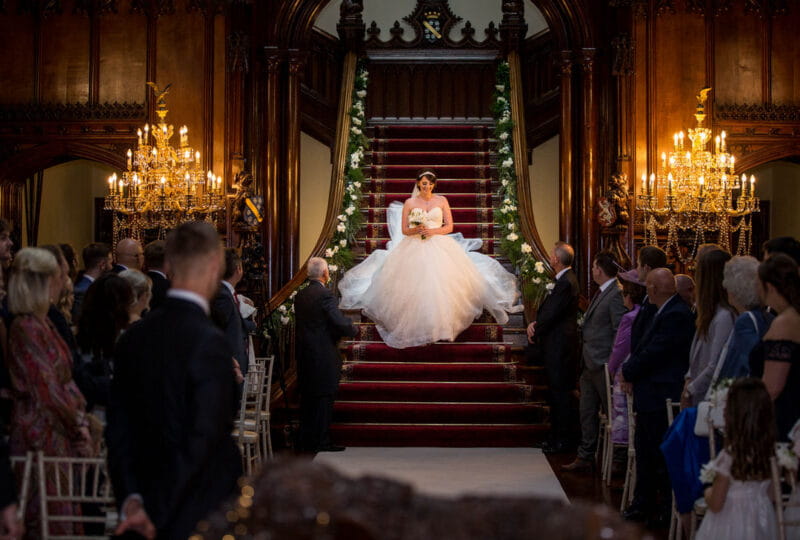 Bride walking down staircase into wedding ceremony - Picture by Peter Rollings Photography