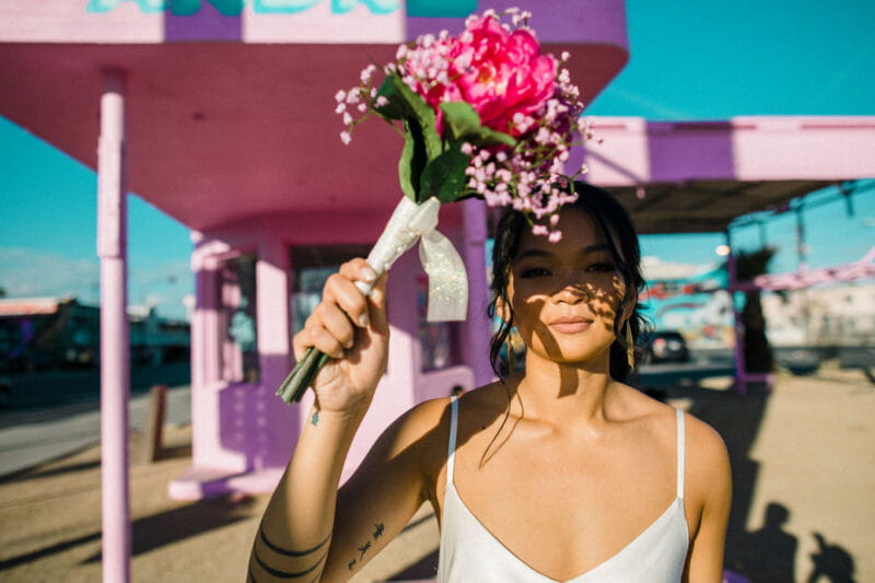 Bride holding up bouquet to shade eyes from the sun - Picture by Chris Barber Photography