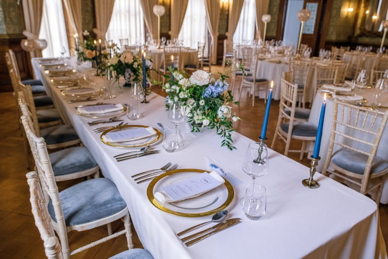 Wedding top table styled with gold rimmed plates and blue candles