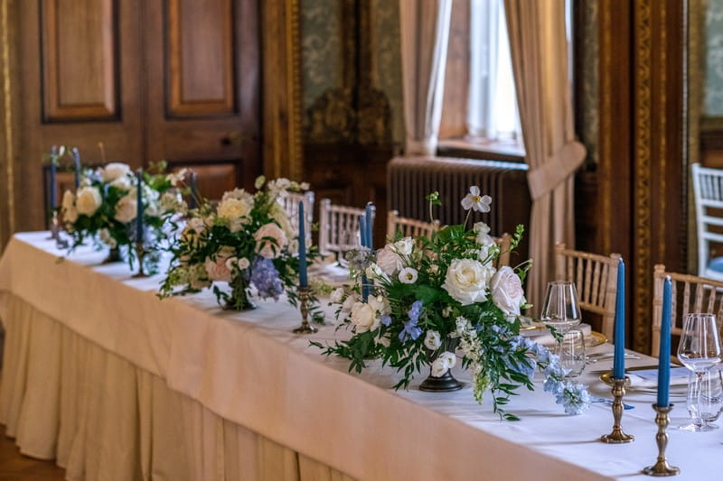 Wedding top table with floral displays of white and blue flowers with foliage