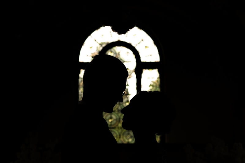 Silhouette of bride and groom's heads against window