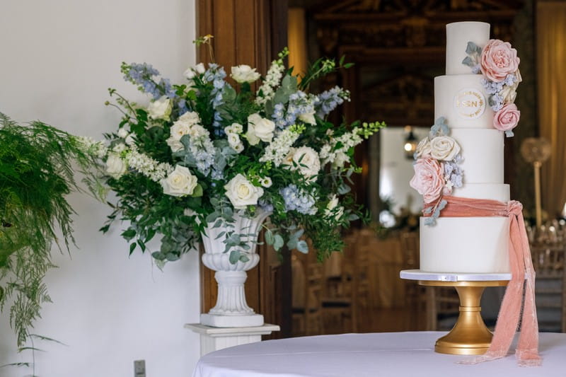 Wedding cake next to large blue and white floral display