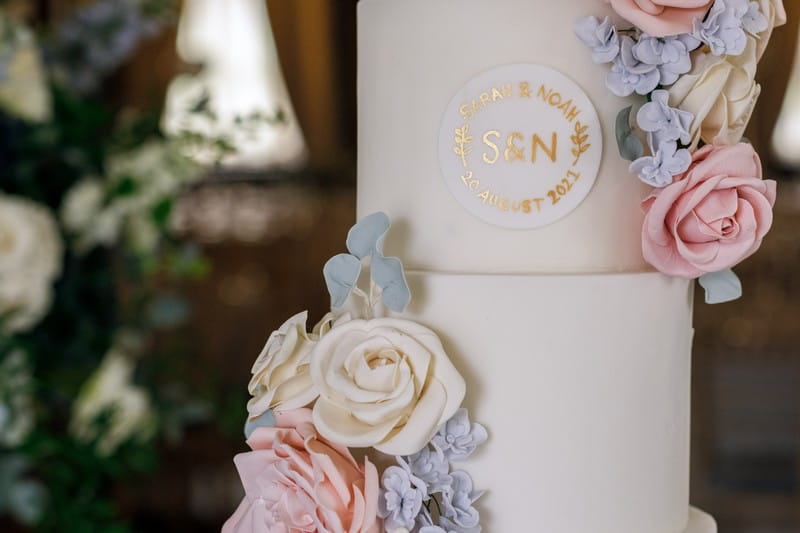 Wedding cake with motif and blue, ivory and pink sugar flowers