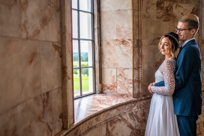 Bride and groom looking out of the window of The Tapestry Room at Hawkstone Hall