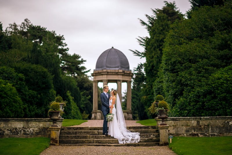 Bride and groom in front of stone gazebo at Hawkstone Hall