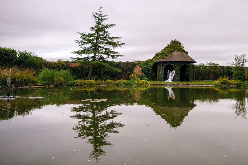 Bride and groom by pond at Hawkstone Hall