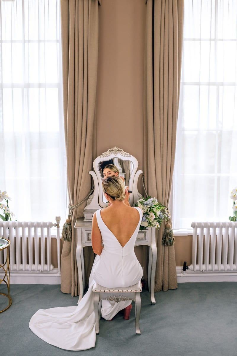 Back of bride sitting at mirror doing make-up