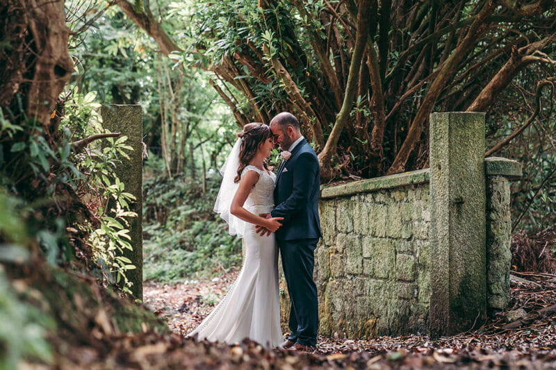 Bride and groom touching heads in woodland area with leaves on ground - Picture by Tracey Warbey Photography