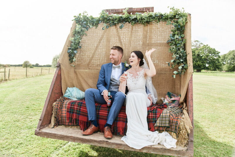 Bride and groom sitting on hay bale seating on digger - Picture by Faye Amare Photography