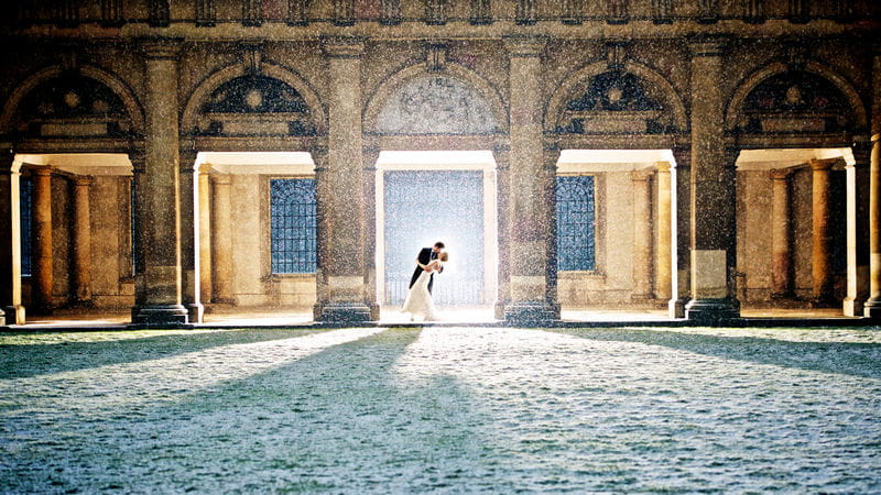 Bride and groom kissing under shelter of building in the snow - Picture by Alex Beckett Photography