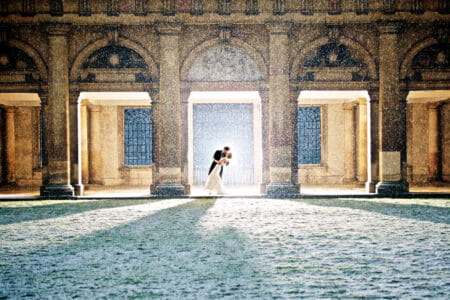 Bride and groom kissing under shelter of building in the snow - Picture by Alex Beckett Photography