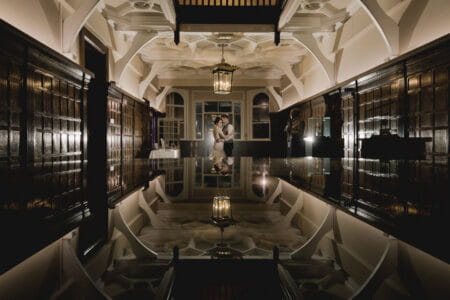 Bride and groom standing in room with their image reflected below them - Picture by Murray Clarke