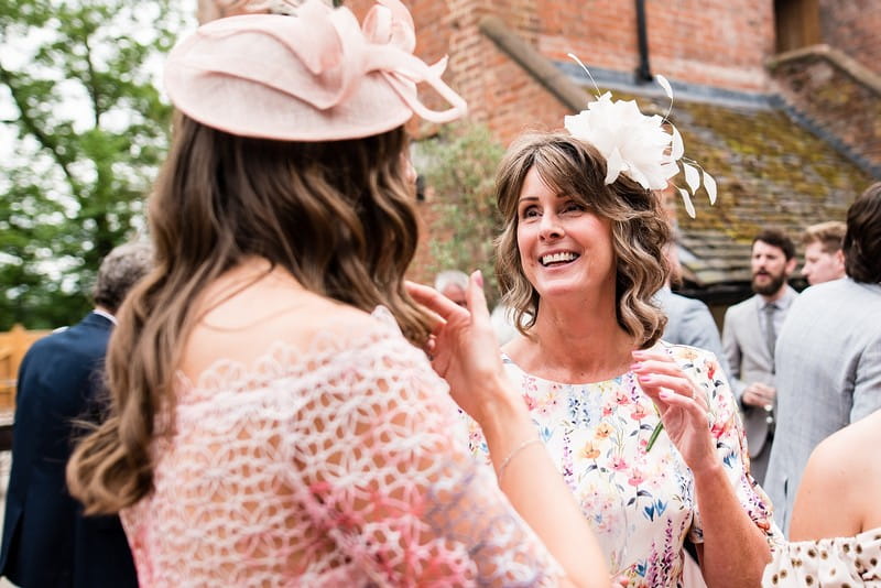 Women in hats talking at wedding