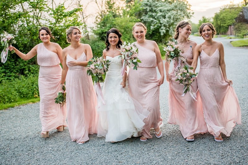 Bride walking with bridesmaids in pink dresses