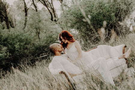 Bride and groom on couch in long grass - Picture by Joice Kelly Photography