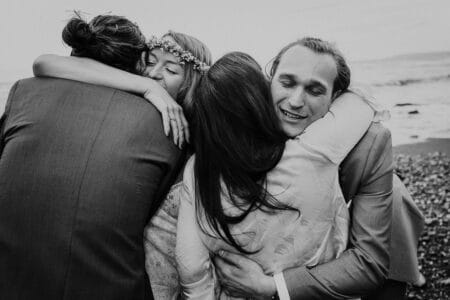 Bride and groom hugging friends on the beach - Picture by Alexa Poppe Wedding Photography