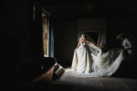 Dark room where mother is helping bride with her wedding dress - Picture by Andy Turner Photography