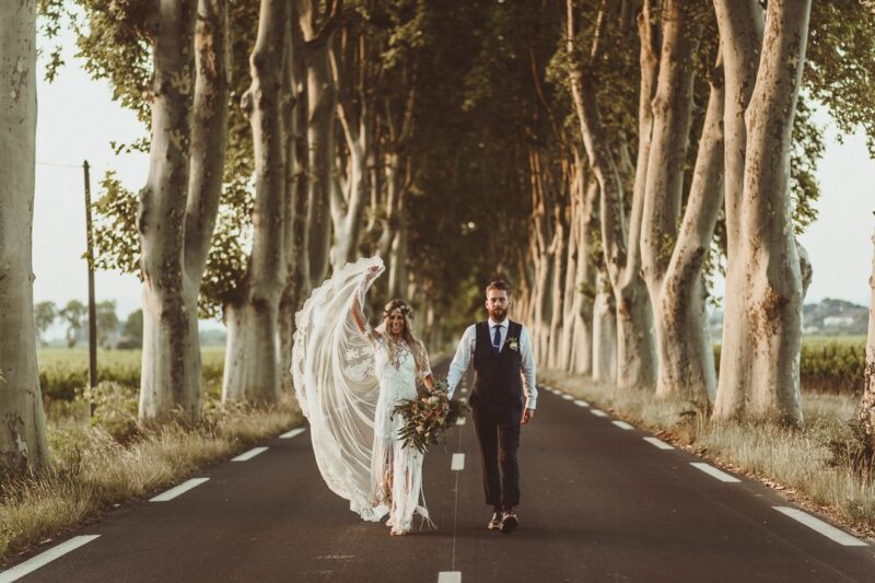 Bride and groom walking down middle of road lined with trees - Picture by Alexa Penberthy Photography