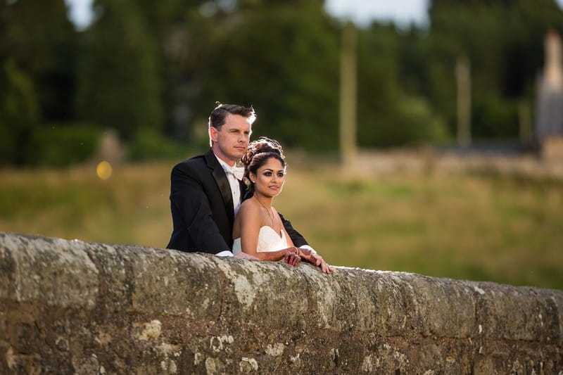Bride and groom leaning on wall