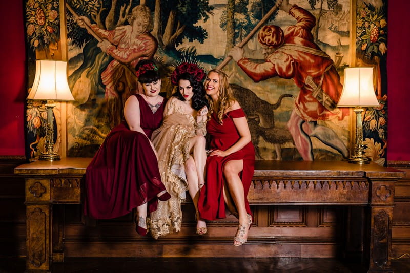 Bride and bridesmaids sitting in front of old tapestry at Thornton Manor