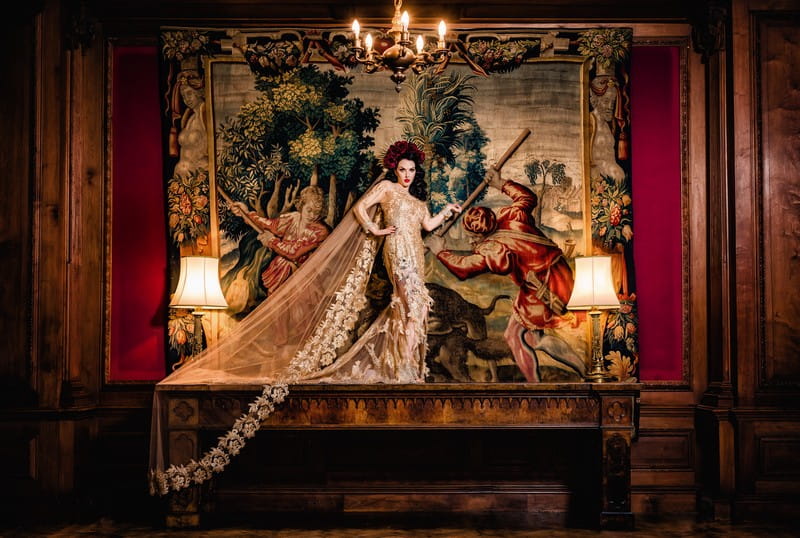 Bride standing on table in front of old tapestry at Thornton Manor