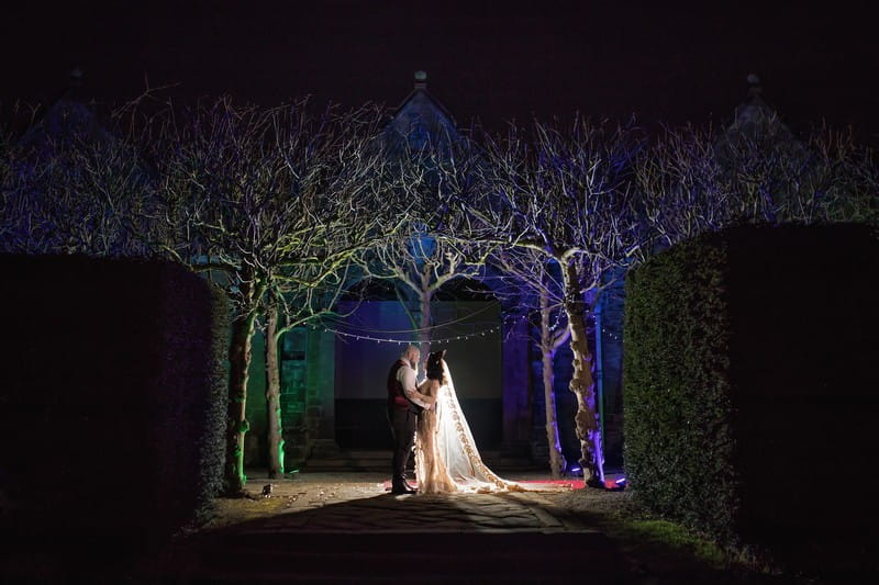 Bride and groom under trees at Thornton Manor at night
