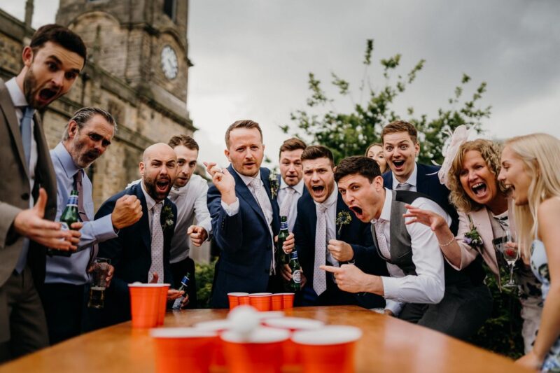 Man playing beer pong at wedding watched by excited guests - Picture by Sawyer and Sawyer Photography