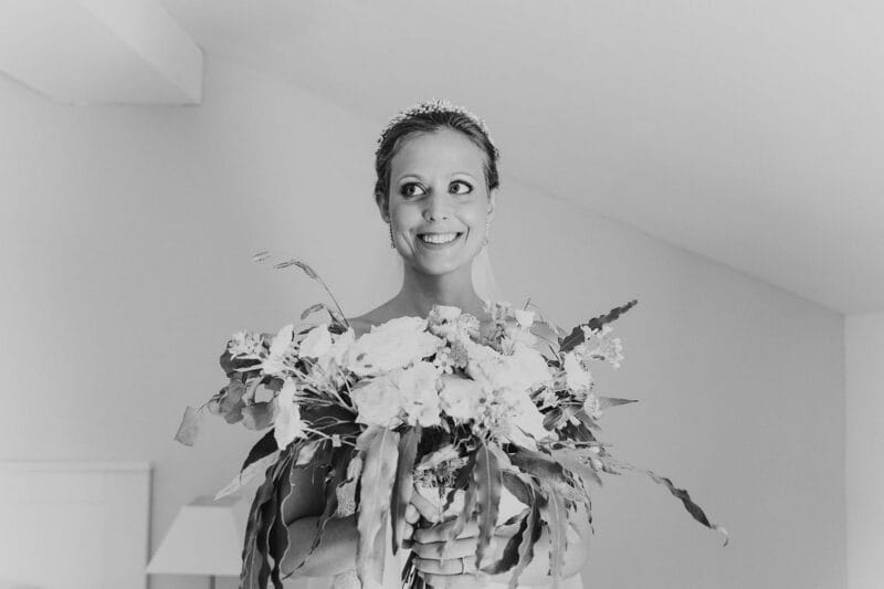 Happy bride smiling as she holds bouquet - Picture by The Sweet Days