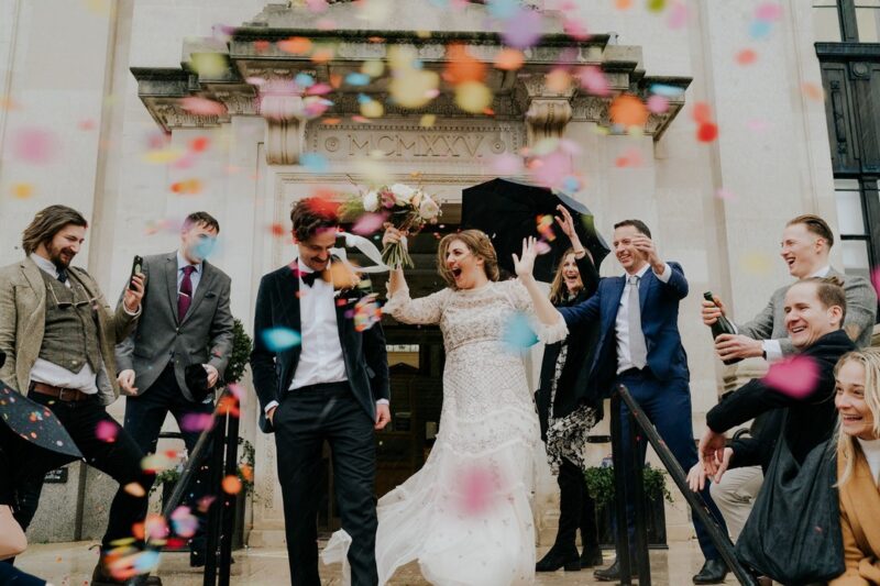 Bride and groom walking through colourful confetti shower - Picture by Joasis Photography